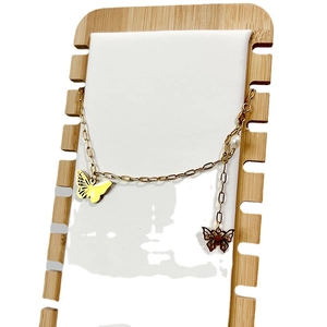 Élégant collier papillon en titane doré avec perles sur un support en bois