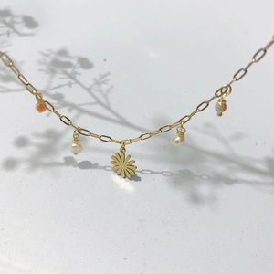 Daisy flower and pearl pendant necklace in gold titanium steel on white background
