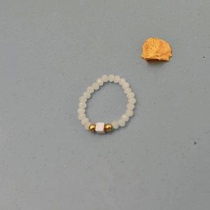Detailed view of handmade beaded ring with white frosted beads and gold accents