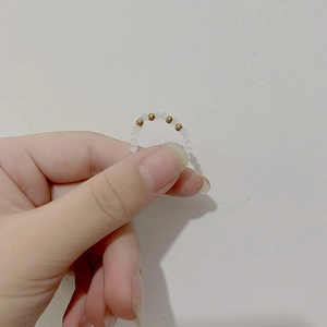 Close-up of a handmade beaded ring with white beads and small golden steel accents