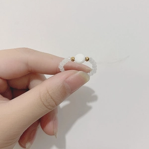 Detail of handmade beaded ring with white translucent beads and gold metal accents