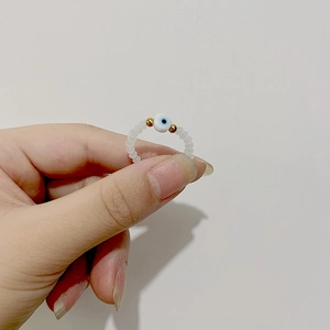 Detail of beaded evil eye ring with white translucent beads and gold accents