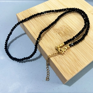 Bohemian faceted black bead necklace with gold lobster clasp on minimalist wood block