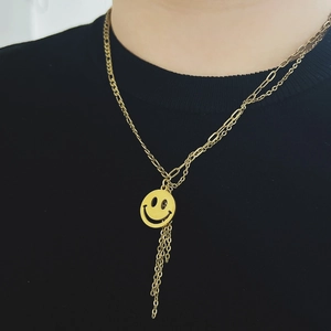 Detail of double-layer gold smile pendant necklace with dangling tassels on black top