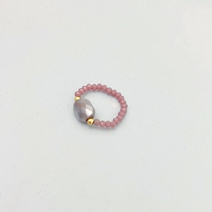 Détail d'une bague perlée avec pierre grise à facettes et petites perles roses