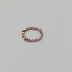 Vue macro d'une bague élastique en perles avec cristaux roses facettés et perles dorées