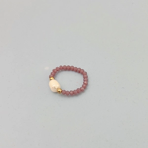 Détail d'une bague élastique en perles violettes facettées et une perle baroque unique