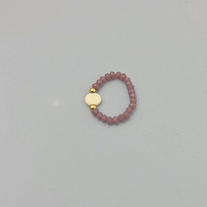 Détail d'une bague élastique en perles violettes avec accents dorés élégants
