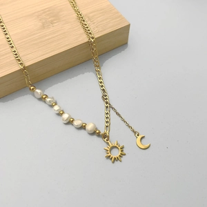 Détail du collier doré à double épaisseur avec pendentifs soleil lune et perles