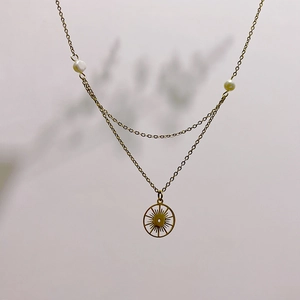 Détail d'un collier doré à plusieurs rangs avec perles blanches et pendentif soleil