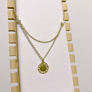 Collier double couche doré avec perles et pendentif soleil sur support en bois
