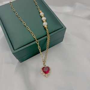 Gros plan du pendentif cœur en pierre rouge avec perles sur une chaîne dorée