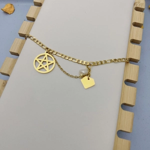 Détail de breloques étoile dorée et perle sur un bracelet chaîne Figaro chic