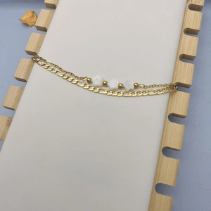 Détail du bracelet double couche en acier titane doré avec trois petites fleurs blanches