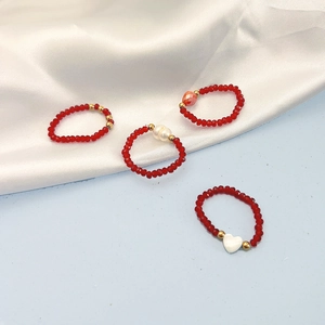 Fashion red crystal bead and pearl shell ring set with elastic cord on silk background