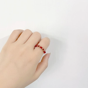 Detailed view of red crystal beads and gold accent rings worn on hand for styling