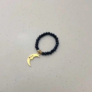 Detail van elastische kralenring met gefacetteerde zwarte kralen en gouden maanbedel
