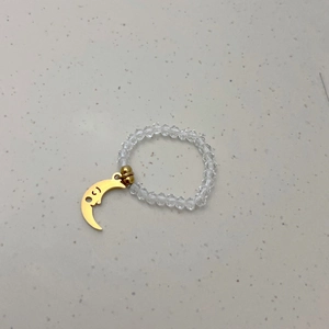 Detail van elastische ring met kristallen kralen en een gouden lachende maan hanger