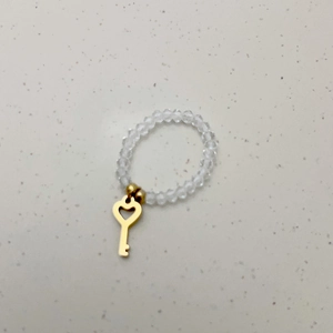 Detail van elastische kralenring met gouden hartvormige sleutelhanger voor vrouwen