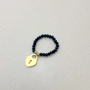 Detail van elastische kralenring met zwarte gefacetteerde kralen en gouden hartslotje