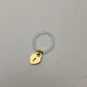 Detail van elastische kralenring met kristallen en een gouden hartvormige slot hanger