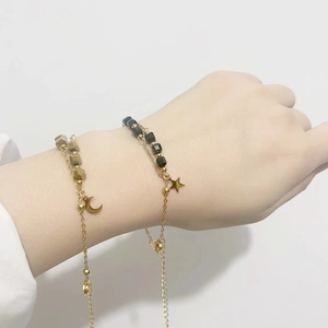 Minimalist gold-plated star and moon bracelets with cubical beads on woman wrist