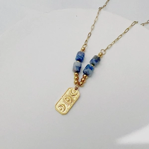 Macro view of 18K gold necklace with Evil Eye sun pendant and blue bead accents