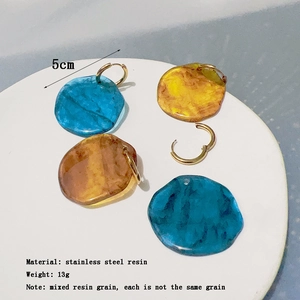 Detailed set of round resin earrings with unique textures in blue, yellow, and amber brown