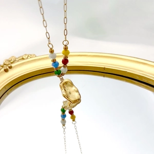 French luxury gold irregular pendant necklace with colorful beads on a mirror surface