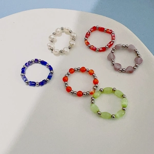 Colorful crystal beads and cat eye stone elastic rings set in a white ceramic dish