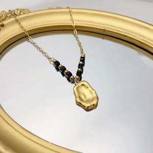 Detail of gold hammered pendant necklace with black beads on a vintage mirror surface