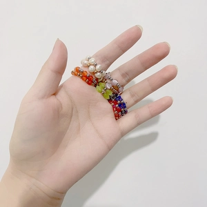 Colorful beaded elastic rings with freshwater pearls and gold accents worn on a hand