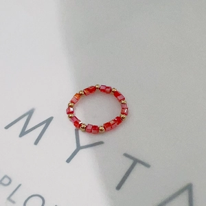 Detail of handmade elastic ring with red faceted beads and gold metal spacers