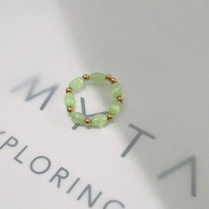 Macro shot of green beaded ring with gold metal beads and elastic stretch design