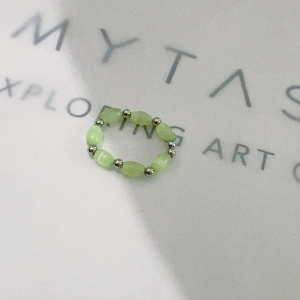 Detail of beaded stretch ring featuring mint green cat eye stone and silver metal beads