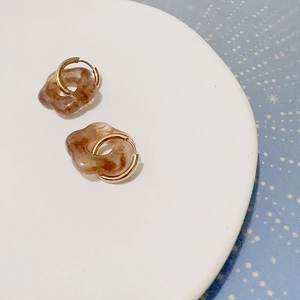 Détail de boucles d'oreilles fleurs en résine ambre avec créoles dorées
