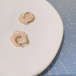 Gros plan détaillé de boucles d'oreilles fleur en résine rose avec anneaux dorés