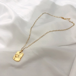 Detail of 18K gold plated tree of life pendant with textured lava finish on silk