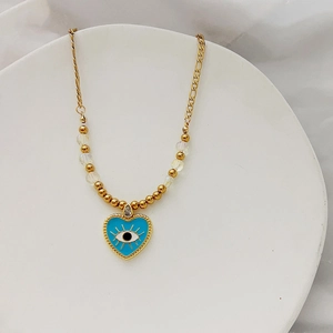 Détail du pendentif cœur œil bleu avec émail, perles dorées et pierre de zircon cubique