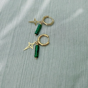 Détail de breloques étoiles dorées et pendentifs cylindres en malachite sur boucles