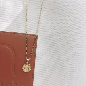 Détail du pendentif soleil en or 18K sur une chaîne trombone élégante et dorée
