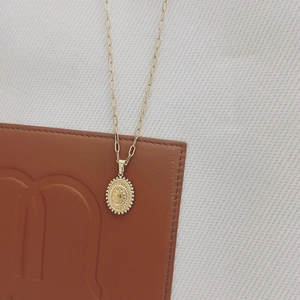 Détail macro du pendentif soleil en or 18 carats sur un collier tendance à trombones