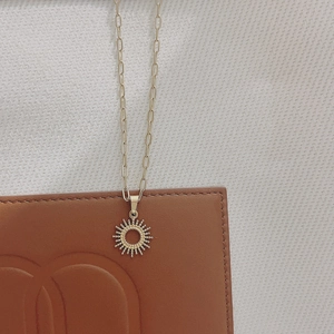 Détail du collier en acier inoxydable plaqué or 18K avec pendentif soleil sur du cuir