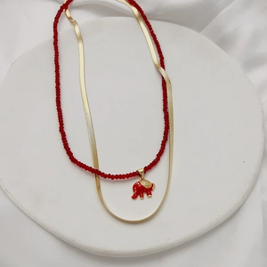 Close-up of double-layered necklace with red beads and golden elephant charm