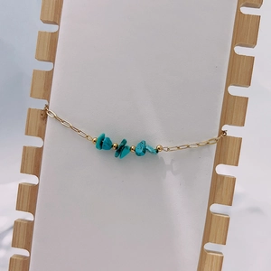Bohemian beaded bracelet with turquoise stones and gold chain on wooden stand