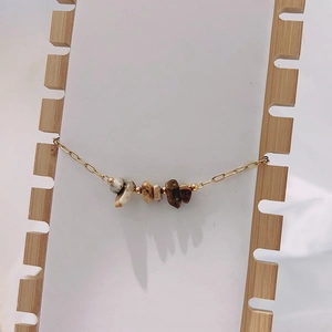 Close-up of bohemian bracelet with irregular natural tiger eye stones and gold chain links