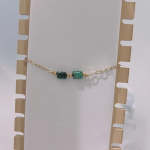 Detail of paperclip chain bracelet with square turquoise stones and gold beads