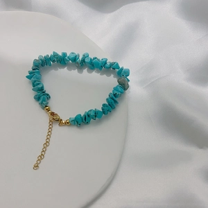 Detailed shot of irregular turquoise stones on a gold-plated stainless steel bracelet