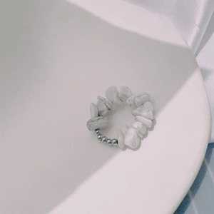 Detalle de piedras naturales blancas y cuentas de acero inoxidable en anillo elástico