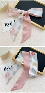 Détail de l'écharpe en soie avec imprimé palmier tropical et noeud sur pierre beige